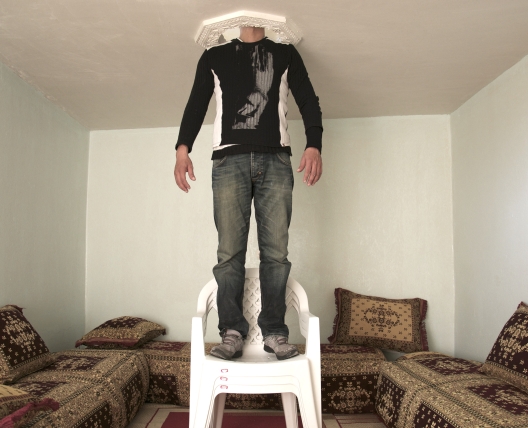 man standing on chair with head in the ceiling 