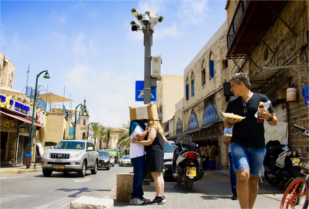 man walking down the street with food and two people with their heads in a box 