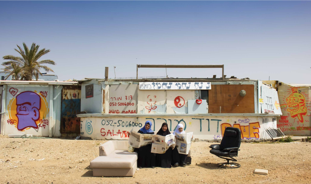 3 women sitting on a couch outside reading the news paper
