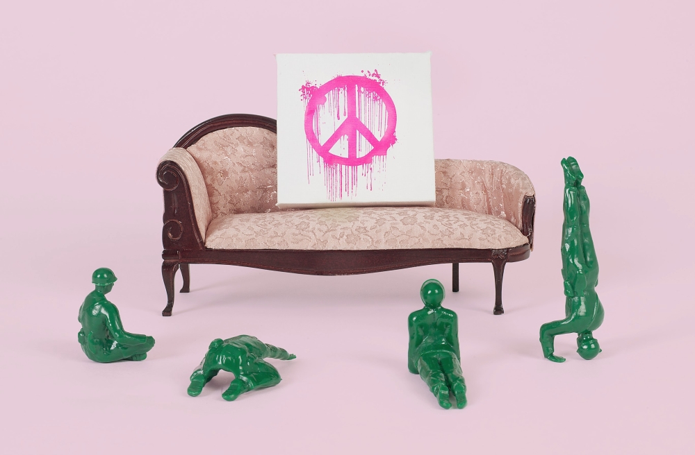 plastic army men in front of a toy couch with a peace sign