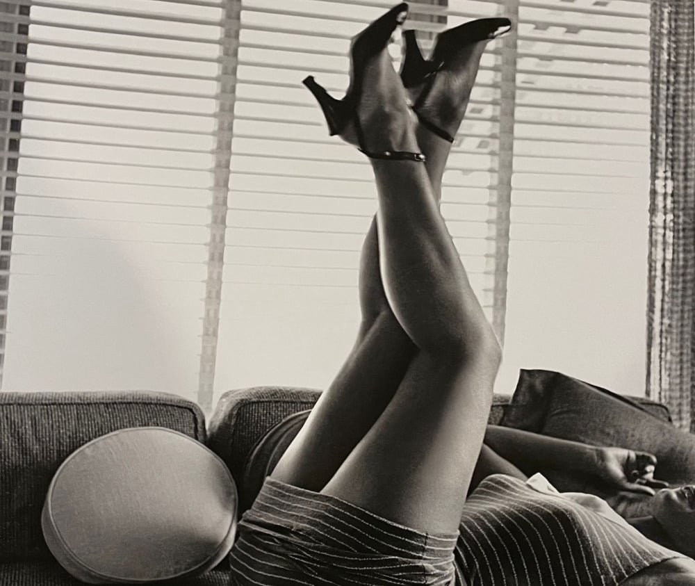 b/w image of a woman laying on a sofa with her legs in the air crossed