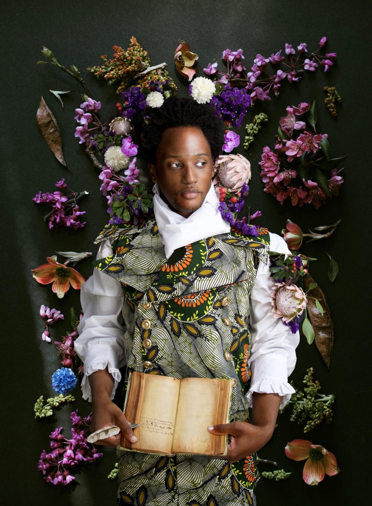 man with book and surrounded by flowers