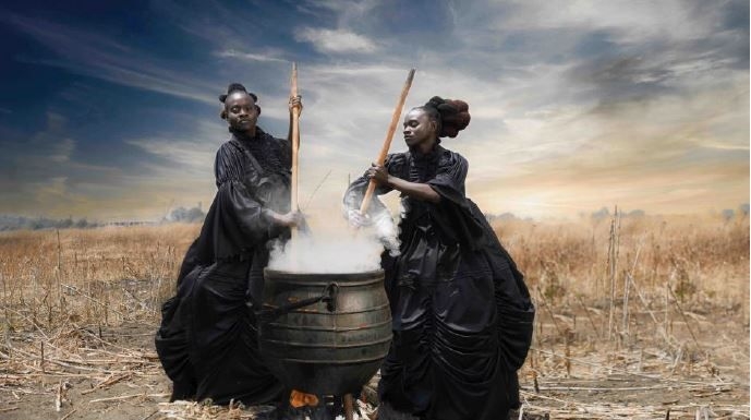 two women with a boiling pot over fire