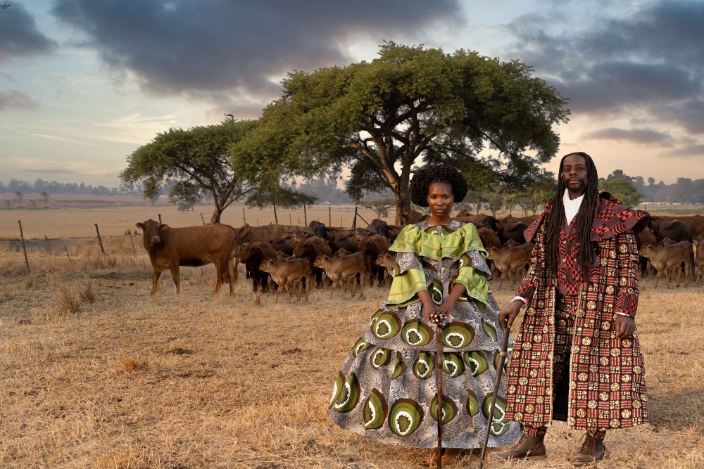 man and woman standing in a field with cattle and dressed up
