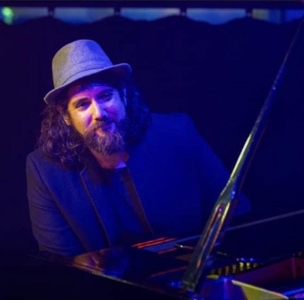 man posing for photo sitting at a piano