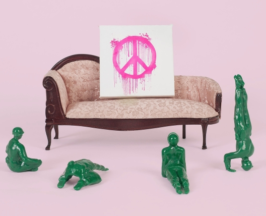 plastic army men in front of a toy couch with a peace sign