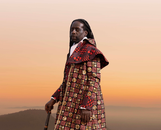 man standing on cliff with walking stick