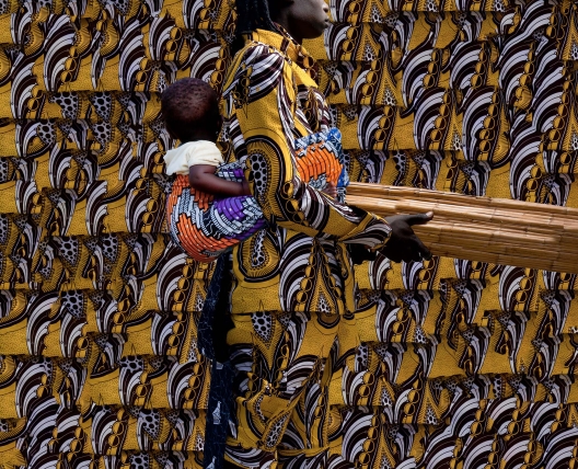 mother with baby on back and carrying wood 