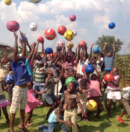 a bunch of children playing with soccer balls 
